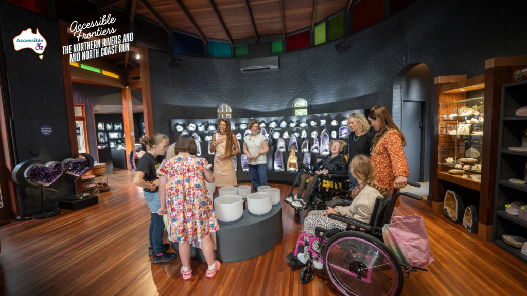 Crystal Castle sound bowl session in a timber-floored room lined with amethyst geodes, with two wheelchair users among the group. Insets show a ramp with handrail to the entrance, and the accessible toilet with grab rails.