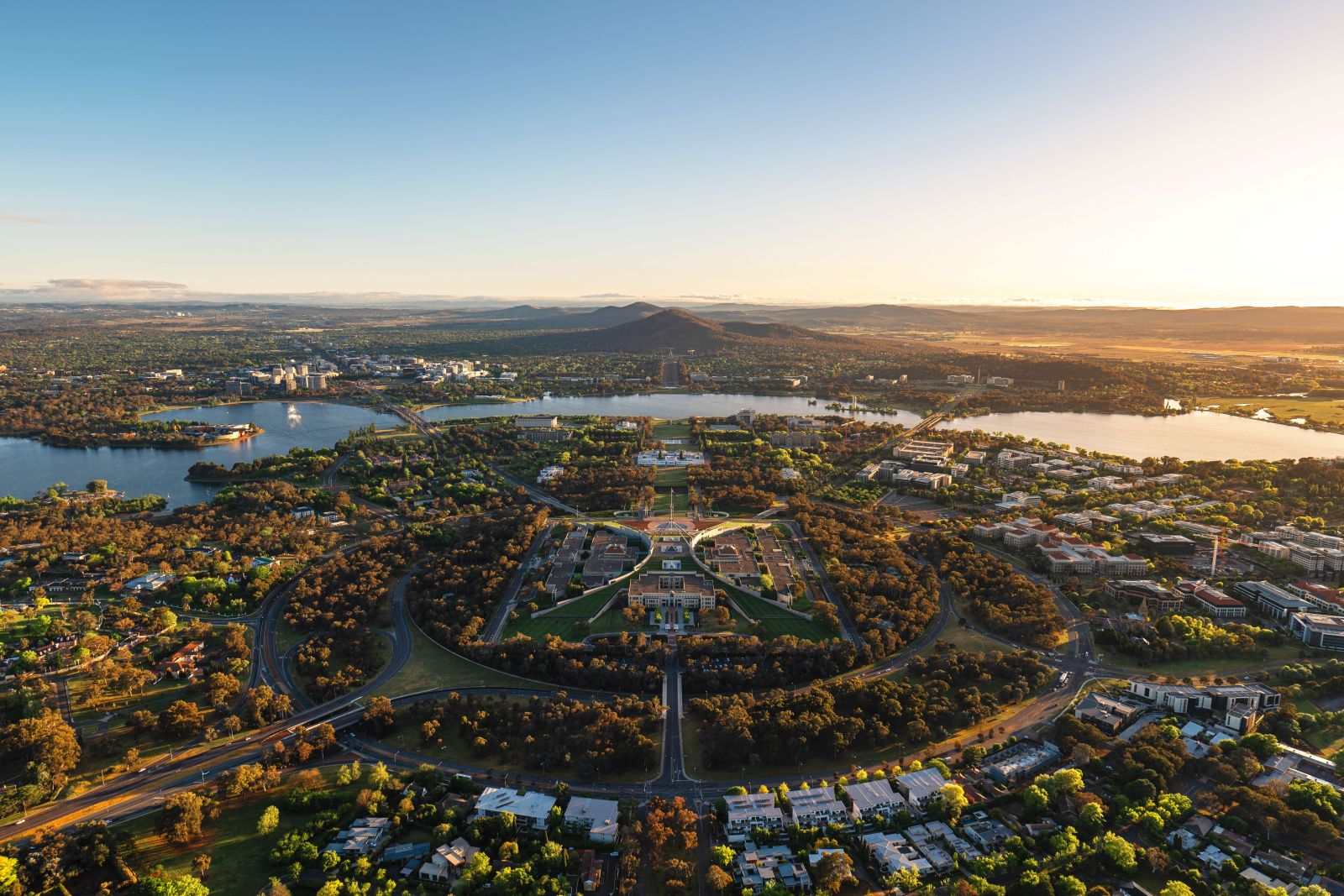 Canberra spread out around Lake Burley Griffin, with the parliamentary triangle and its wide boulevards laid out below a clear sky.