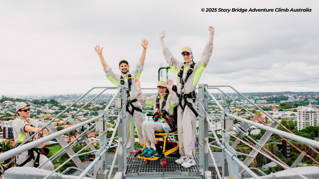 Person in a wheelcair accompanied by two men atop the Story Bridge in Australia.