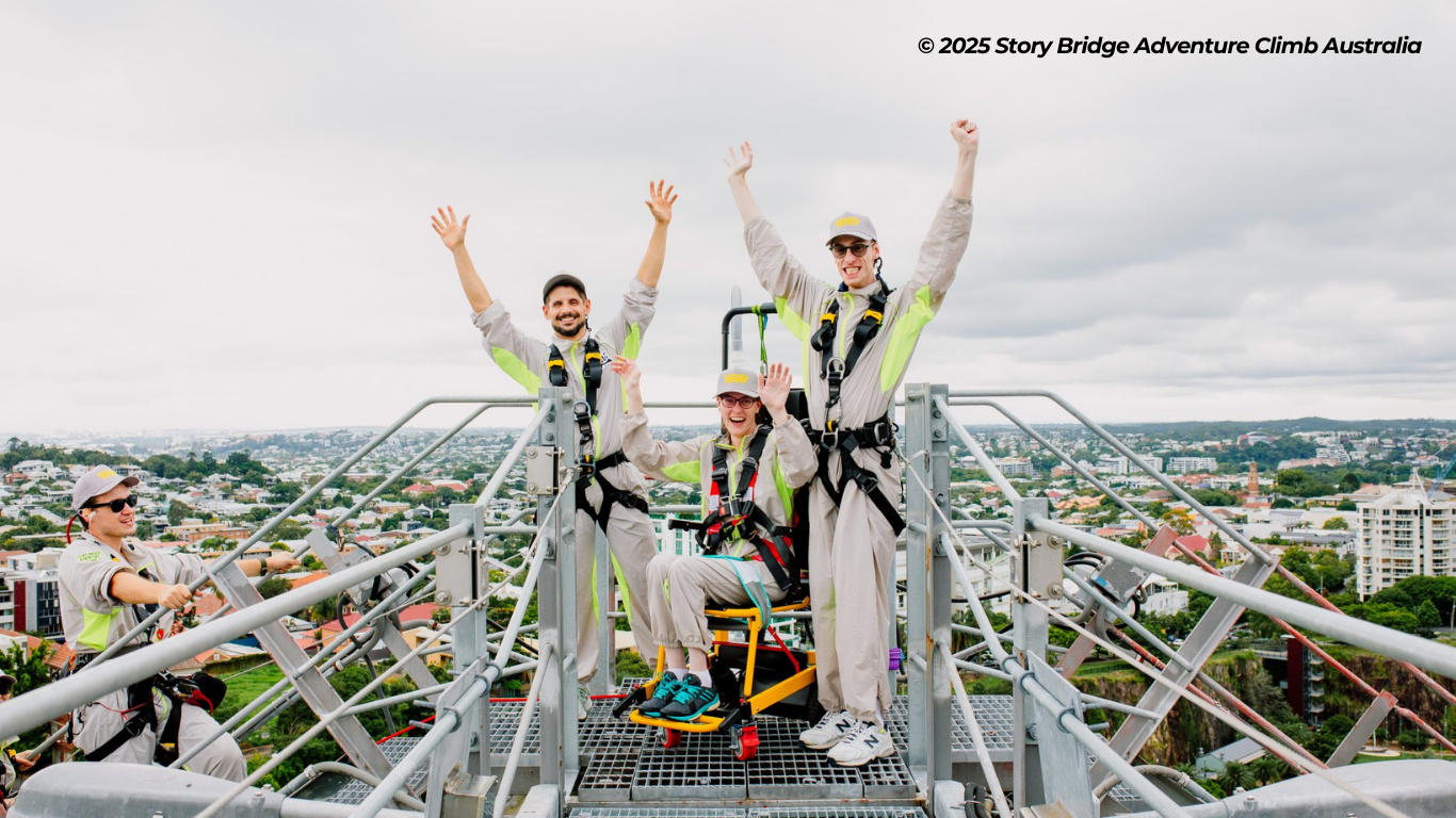 Person in a wheelcair accompanied by two men atop the Story Bridge in Australia.